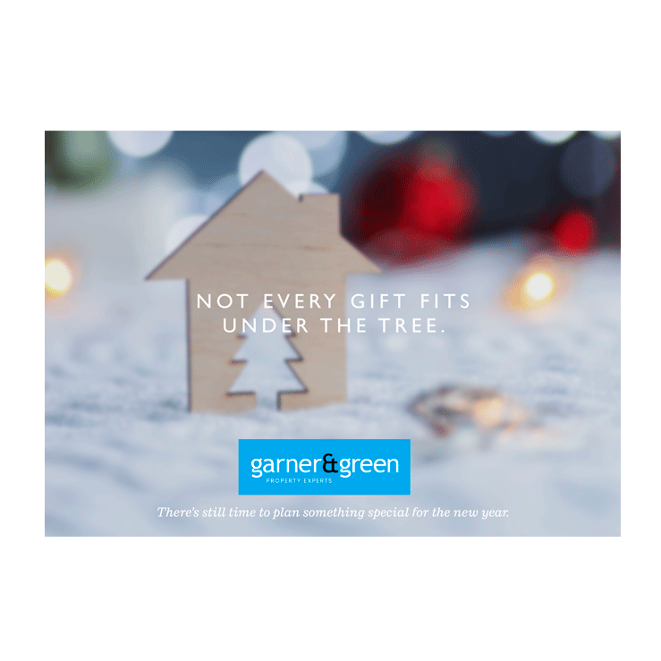 Wooden house ornament with a tree cut-out surrounded by festive lights